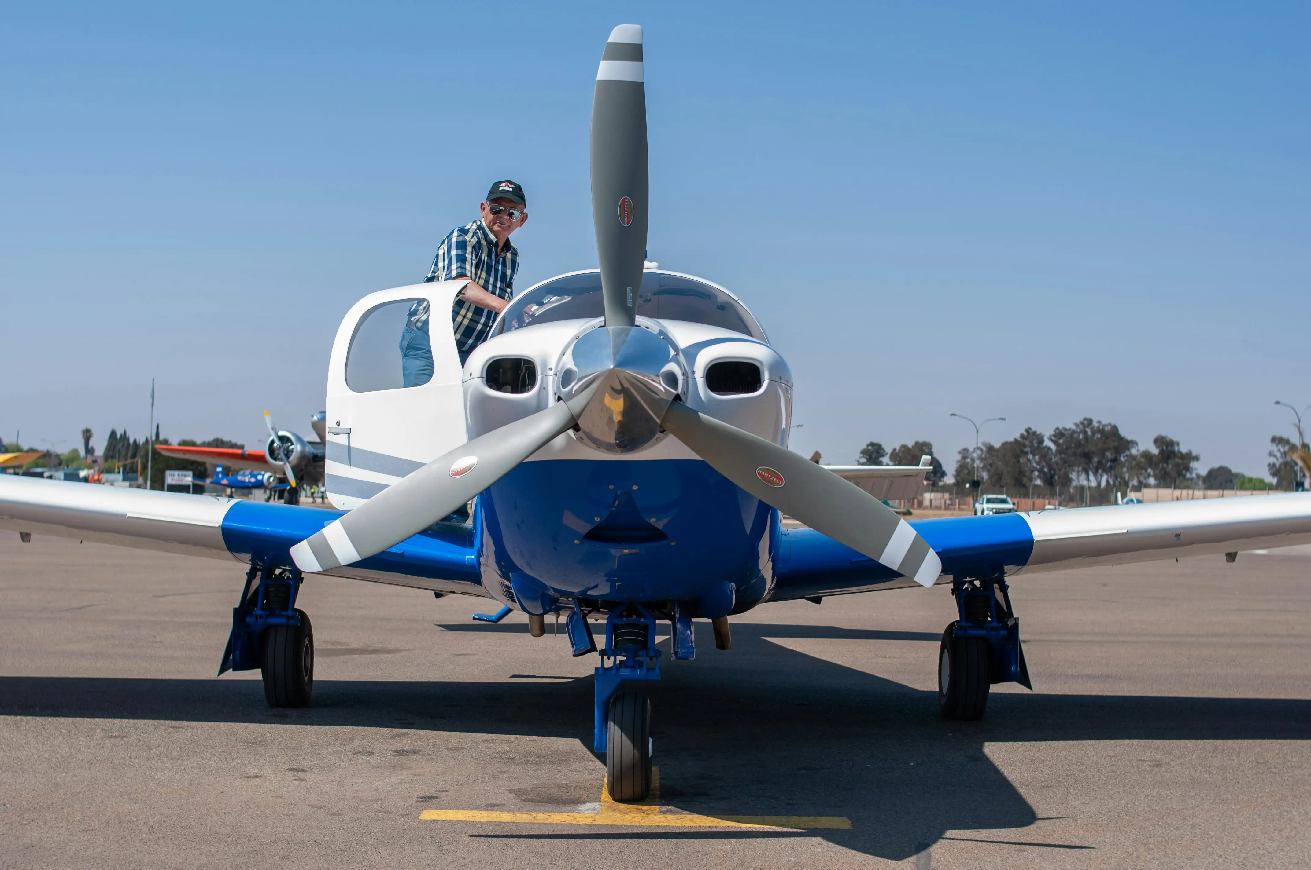 Pilot standing by aircraft on ground by Steward Masweneng