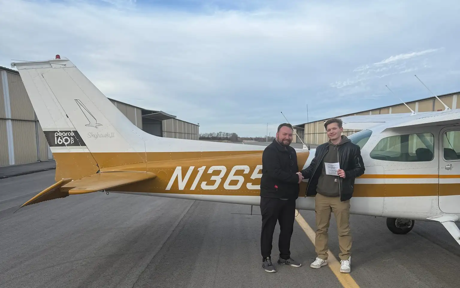 Student passing checkride - Student and CFI shaking hands at Pilot Instructional Center flight school cropped version
